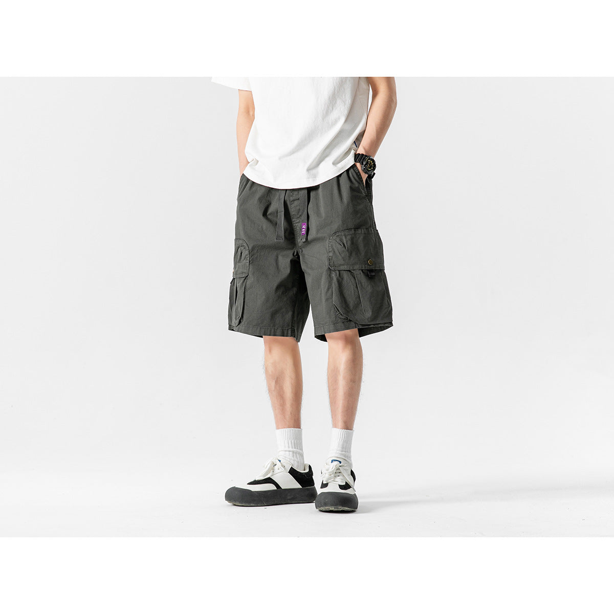 Front view of a model wearing dark gray cargo shorts with large flap pockets and a drawstring waist.