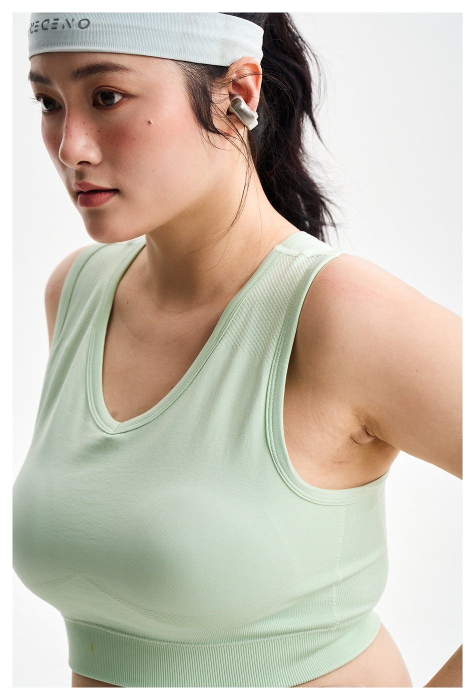 Close-up of a pale mint sleeveless crop top showing its V-neck, armhole seams, and ribbed hem.