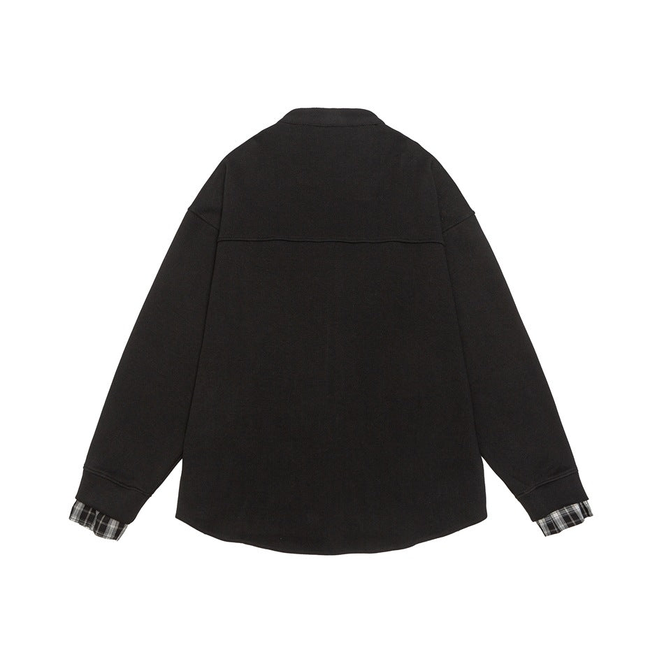 Back view of a black long-sleeved shirt with a short stand collar and plaid fabric peeking from the cuffs.