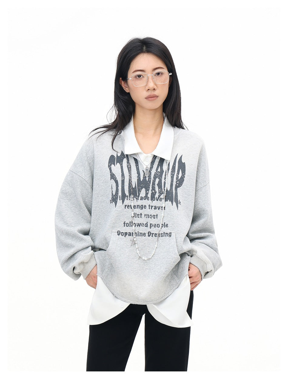 Front view of a model wearing a light gray sweatshirt with a black chest graphic, white collar, and layered shirt hem.