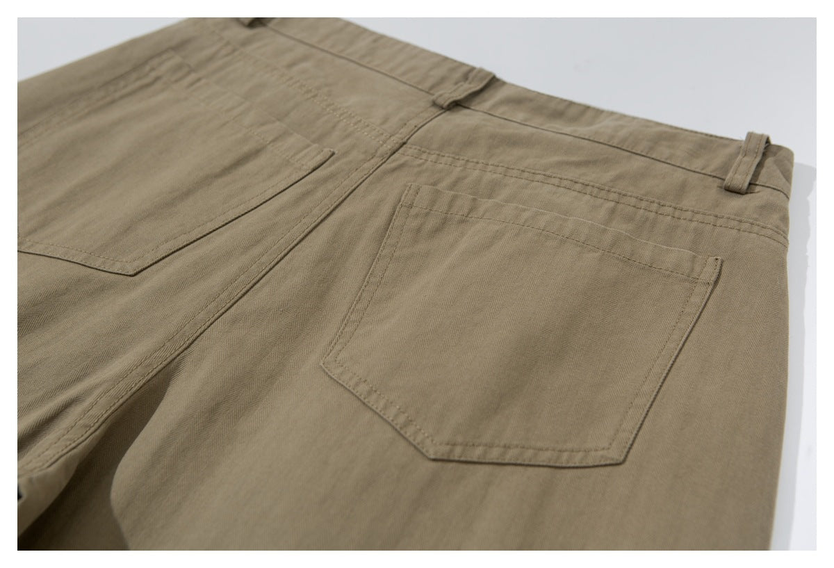 Close-up of the back pockets, waistband, and belt loops on khaki trousers laid flat.