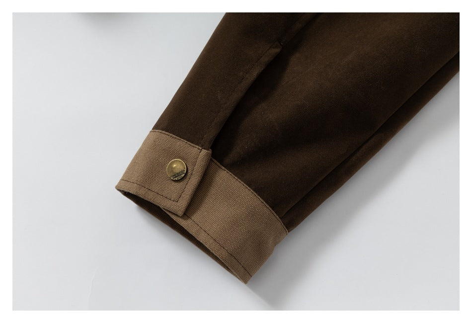 Close-up of a dark brown sleeve cuff with a tan adjustable tab and brass-tone button.