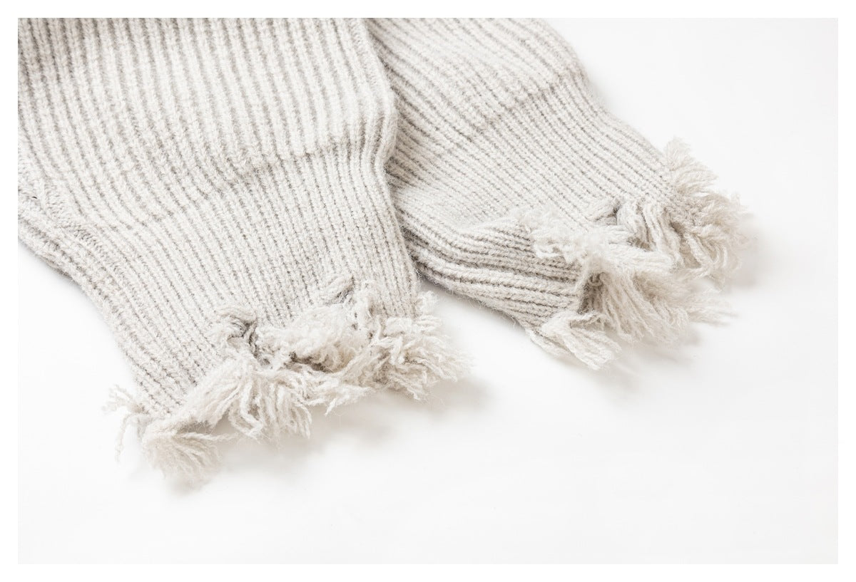 Close-up of two ivory rib-knit cuffs with fringed edges.