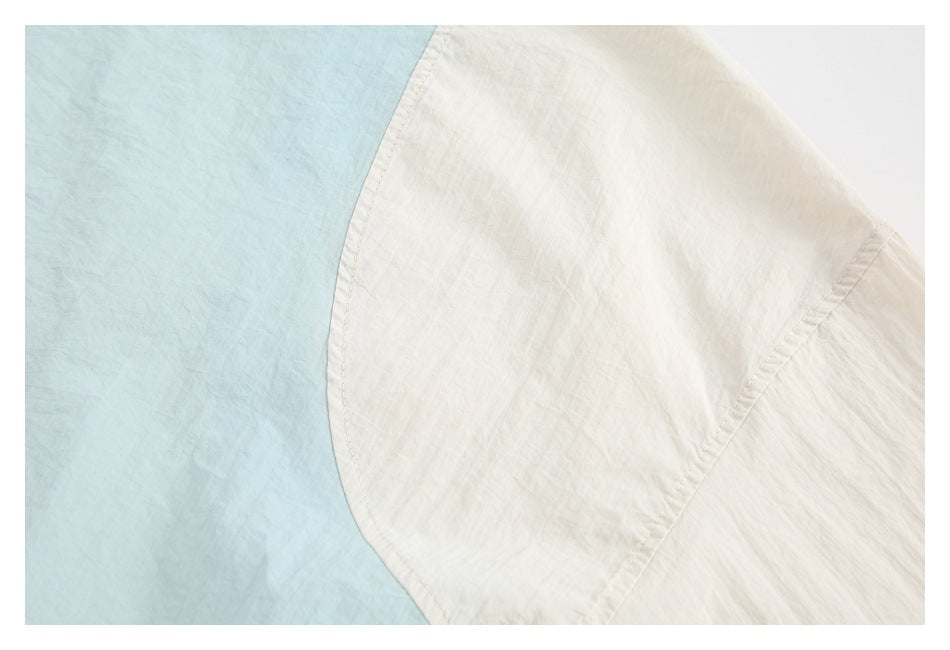 Close-up of a curved seam joining pale blue and ivory bedding fabric.
