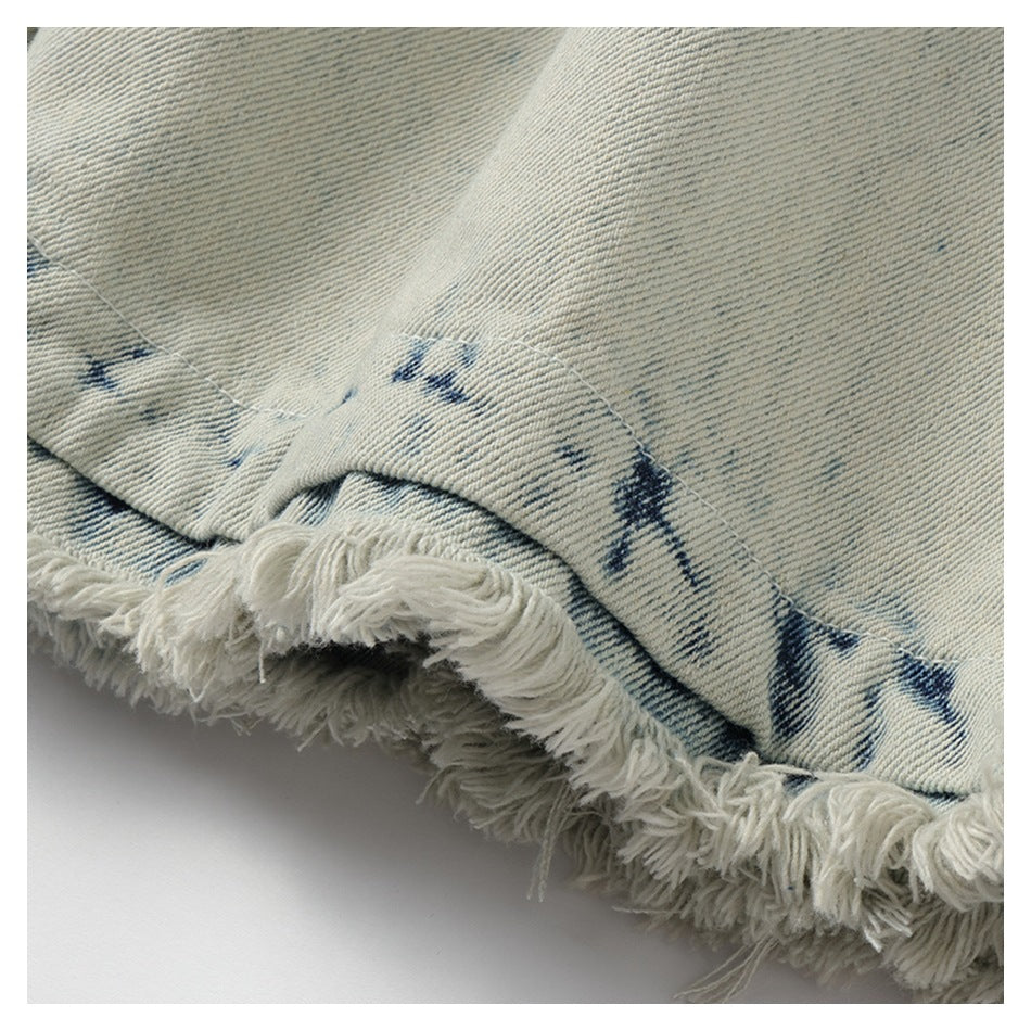 Close-up of a light-wash denim hem with dark blue markings and a thick, frayed edge.