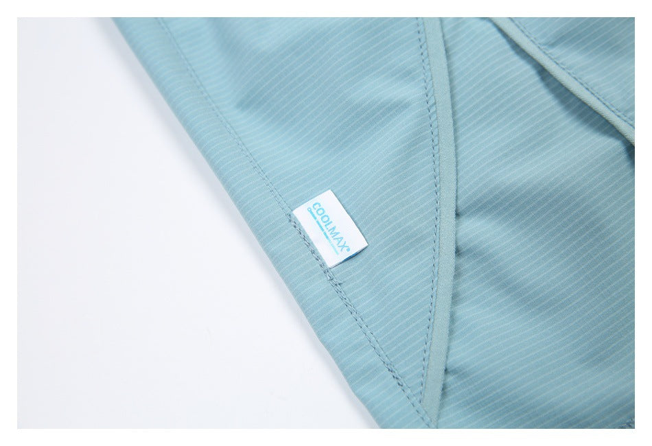 Close-up of a small COOLMAX tag stitched onto light blue striped fabric.