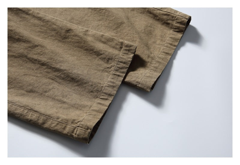 Close-up of the olive-brown pants showing a straight stitched hem and fabric edge.