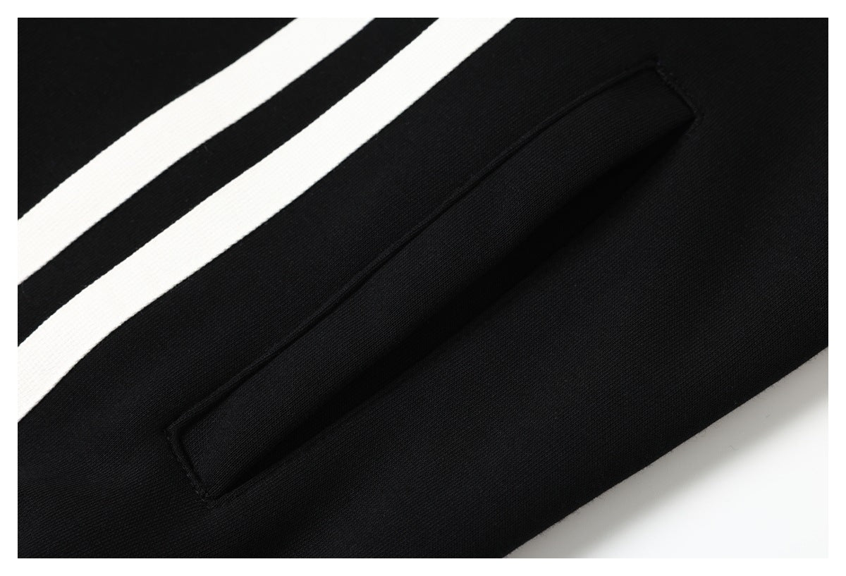 Close-up of a black garment with two white stripes and a narrow welt pocket.