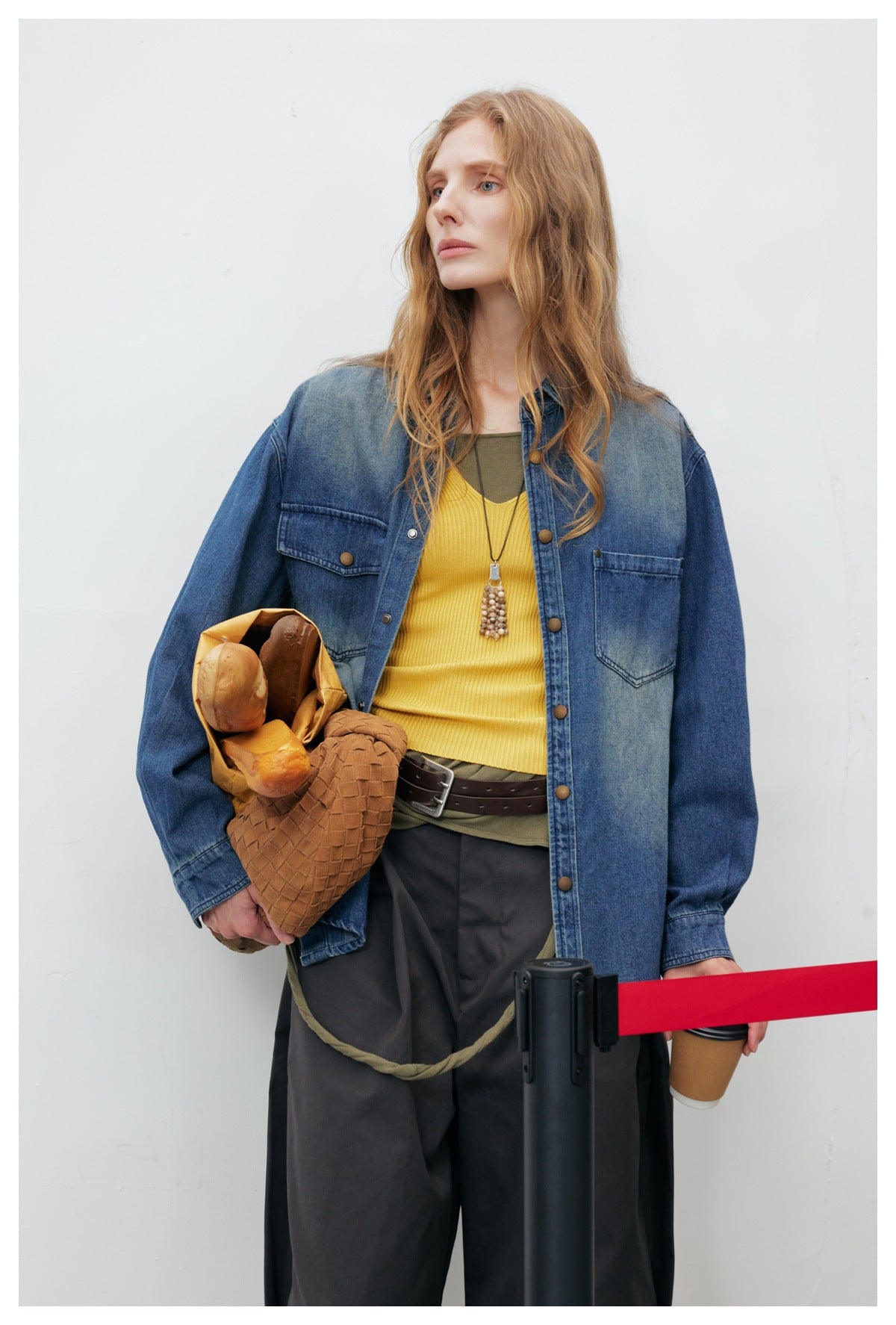 Model wearing an oversized blue denim shirt jacket with chest pockets and snap buttons over a yellow top.