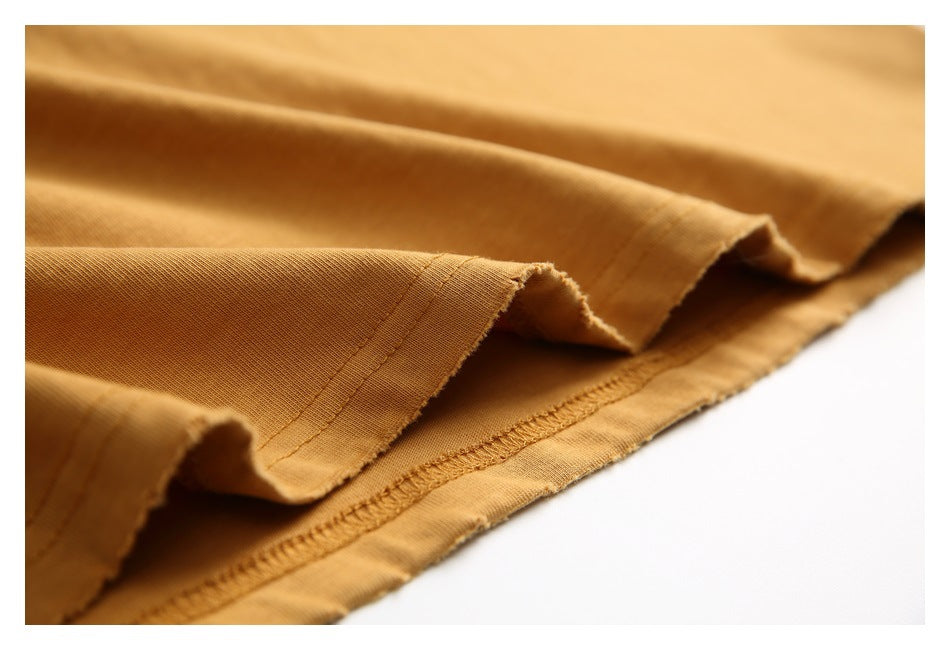 Close-up of folded mustard-gold shirt fabric and its stitched hem.