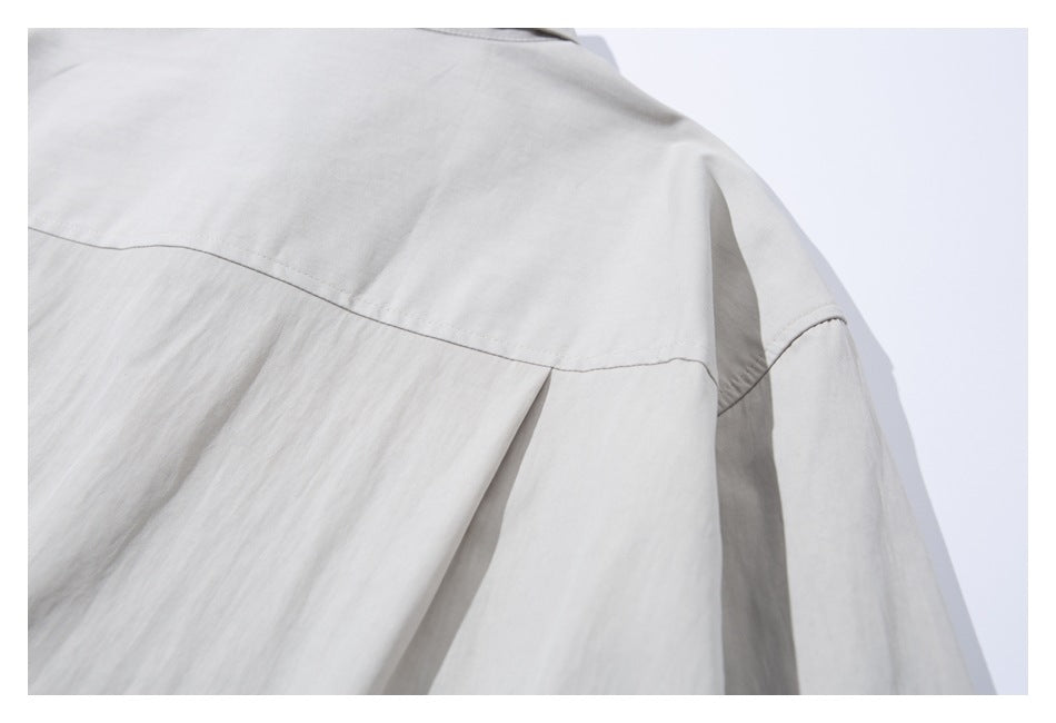 Close-up of the light gray shirt's back yoke seam and central pleat.