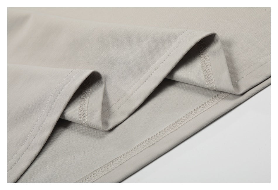 Close-up of the light gray T-shirt's folded hem and overlocked inside stitching.