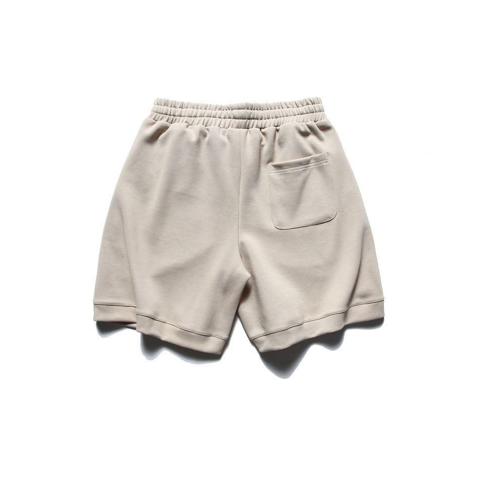 Back view of light beige shorts with an elastic waistband, a patch pocket, and wide hems.