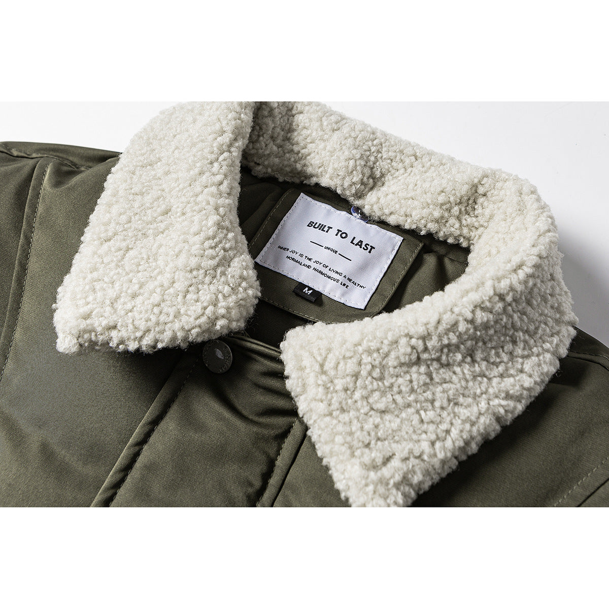 Close-up of the olive jacket's cream sherpa collar, inner label and upper front.
