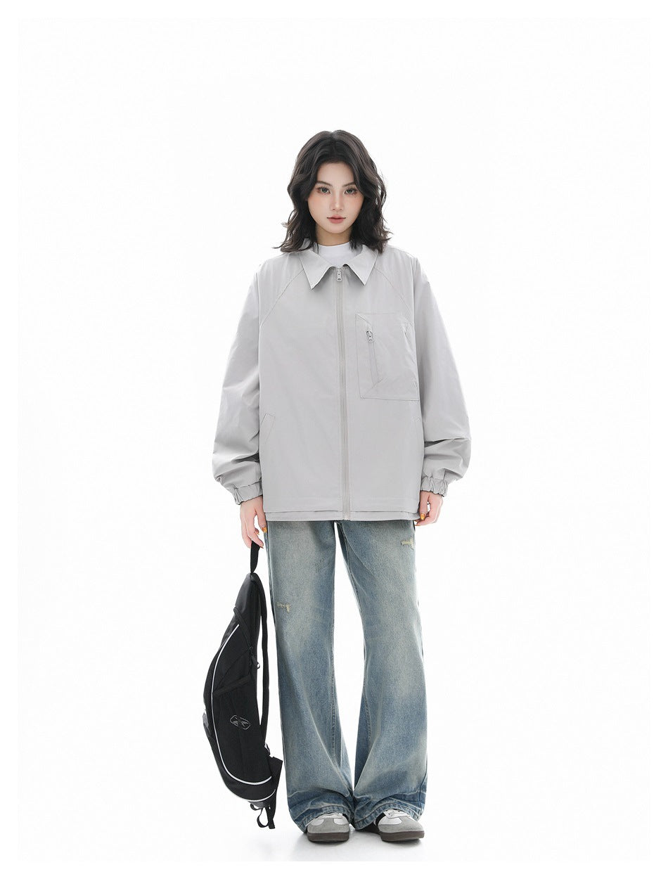 Full-length model wearing a light gray zip-front jacket with a pointed collar and chest pocket, paired with loose jeans.