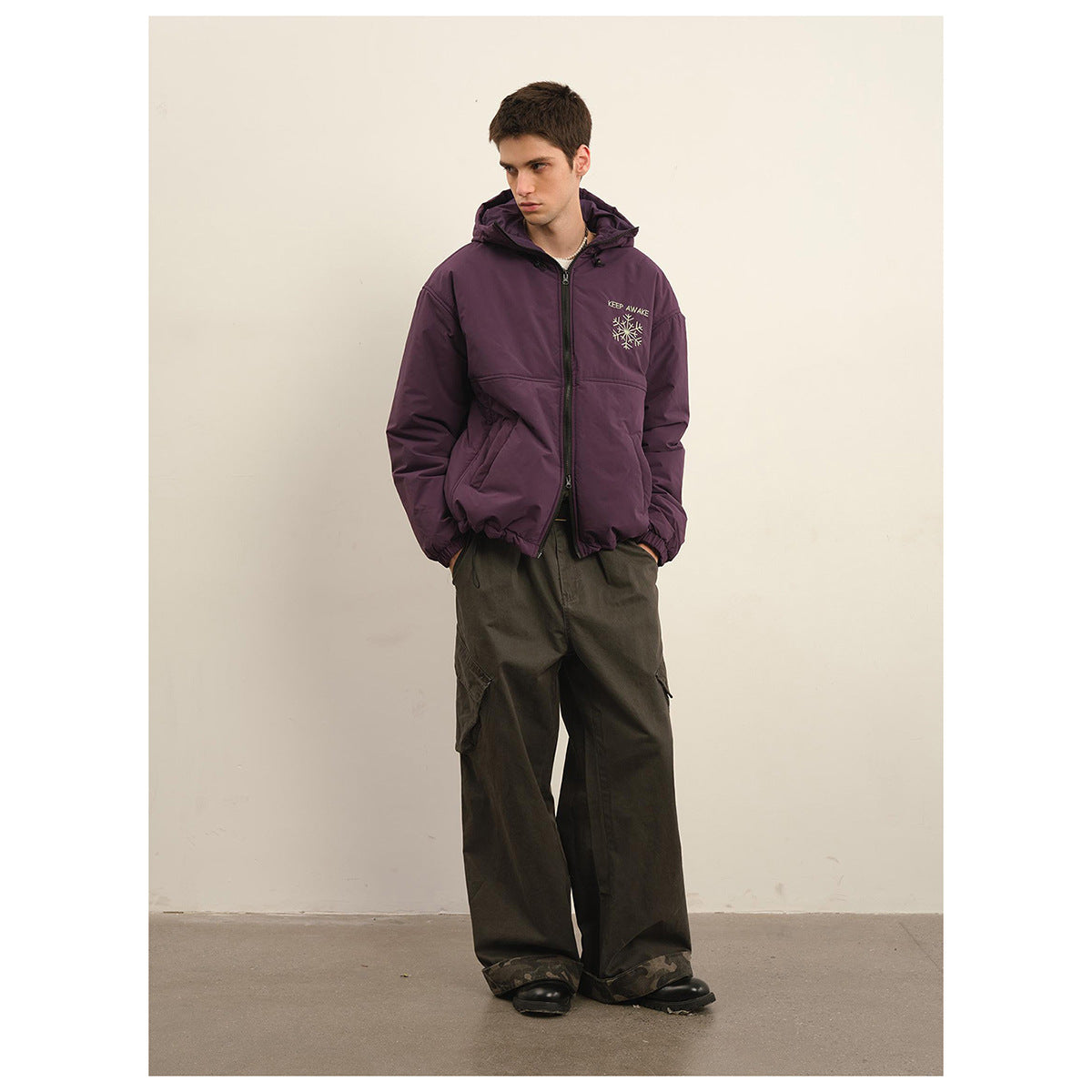 Full-length model wearing a plum hooded zip jacket with light chest embroidery and loose dark cargo pants.
