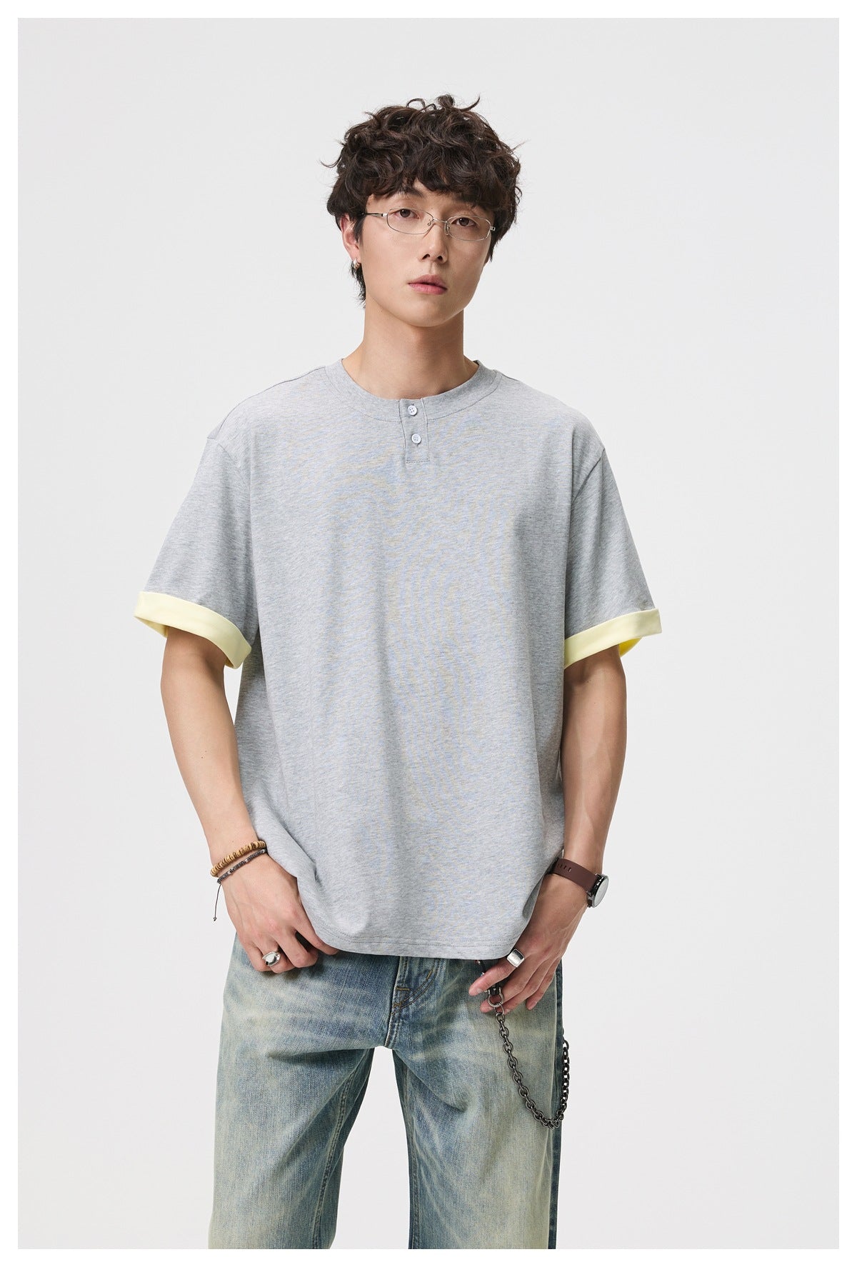 Model wearing a light gray short-sleeve Henley shirt with pale yellow rolled cuffs.