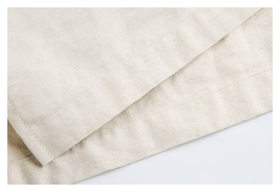 Close-up of a folded, stitched hem on light beige fabric.
