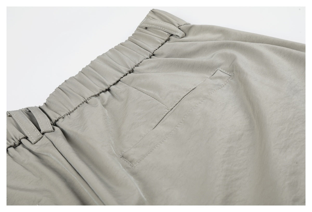 Close-up of a rear pocket and elasticated waistband with belt loops on light gray-beige trousers.