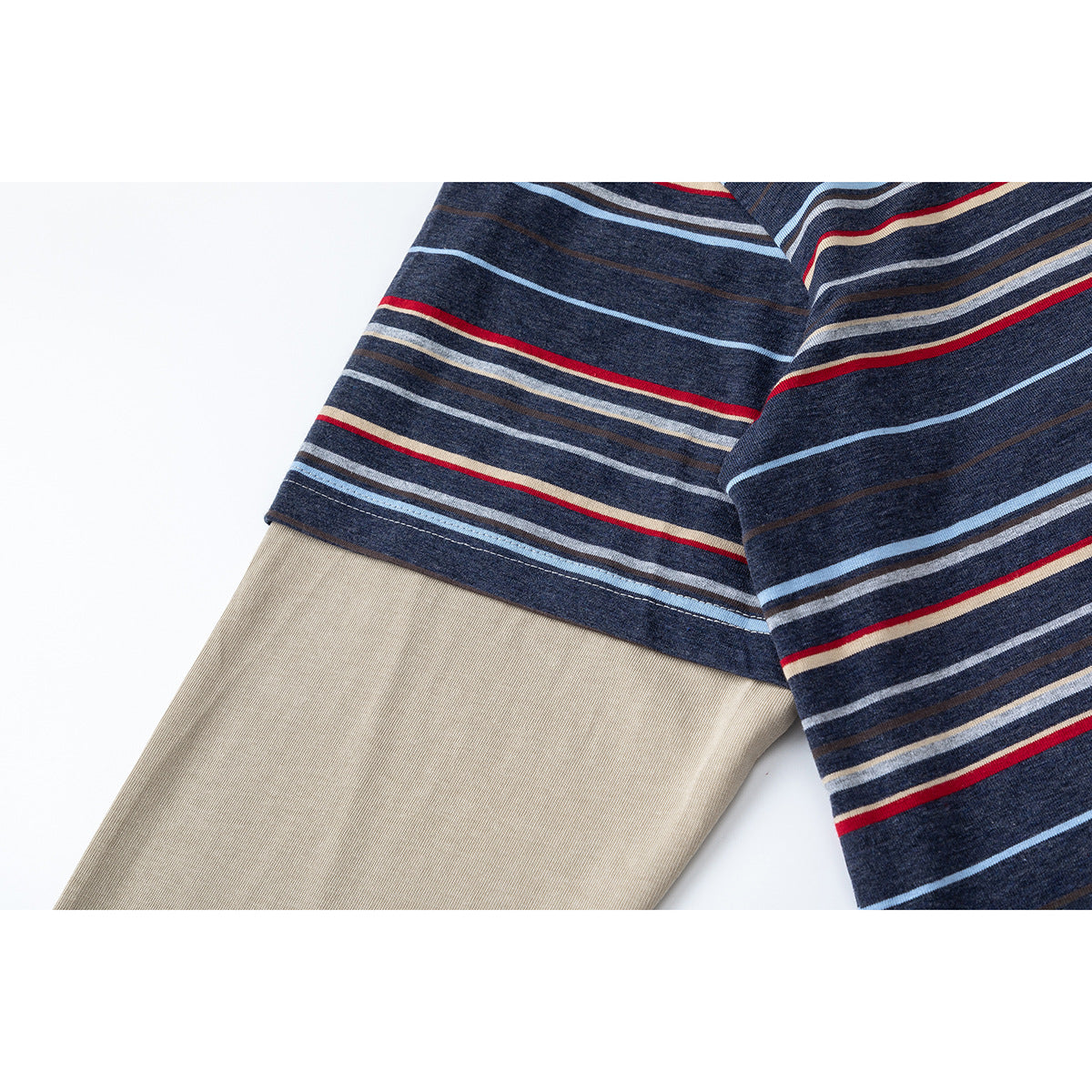 Close-up of a navy striped short sleeve layered over a plain beige long sleeve.