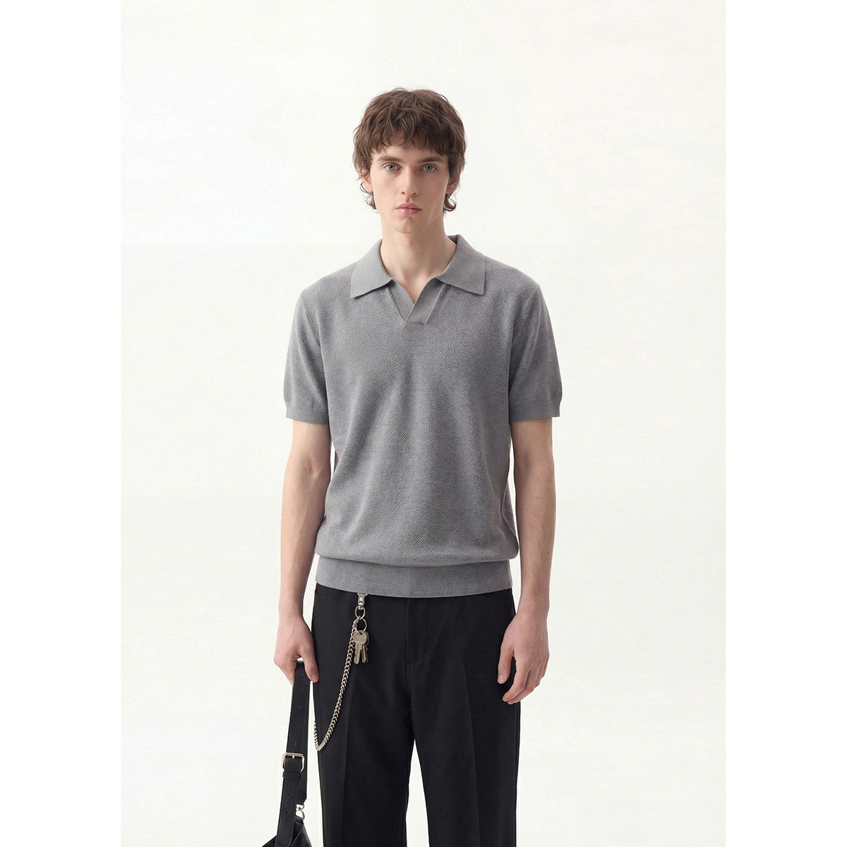 Front view of a model wearing a textured gray short-sleeve polo with a notched collar and black trousers.