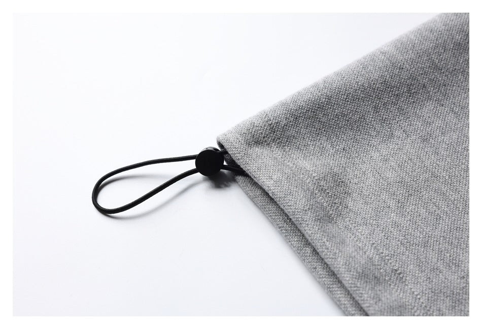 Close-up of a black elastic cord and toggle attached to the edge of a gray garment.