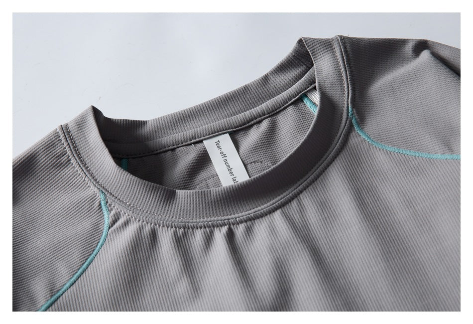 Close-up of the gray pullover’s ribbed crew neckline, turquoise shoulder piping, and inner label.