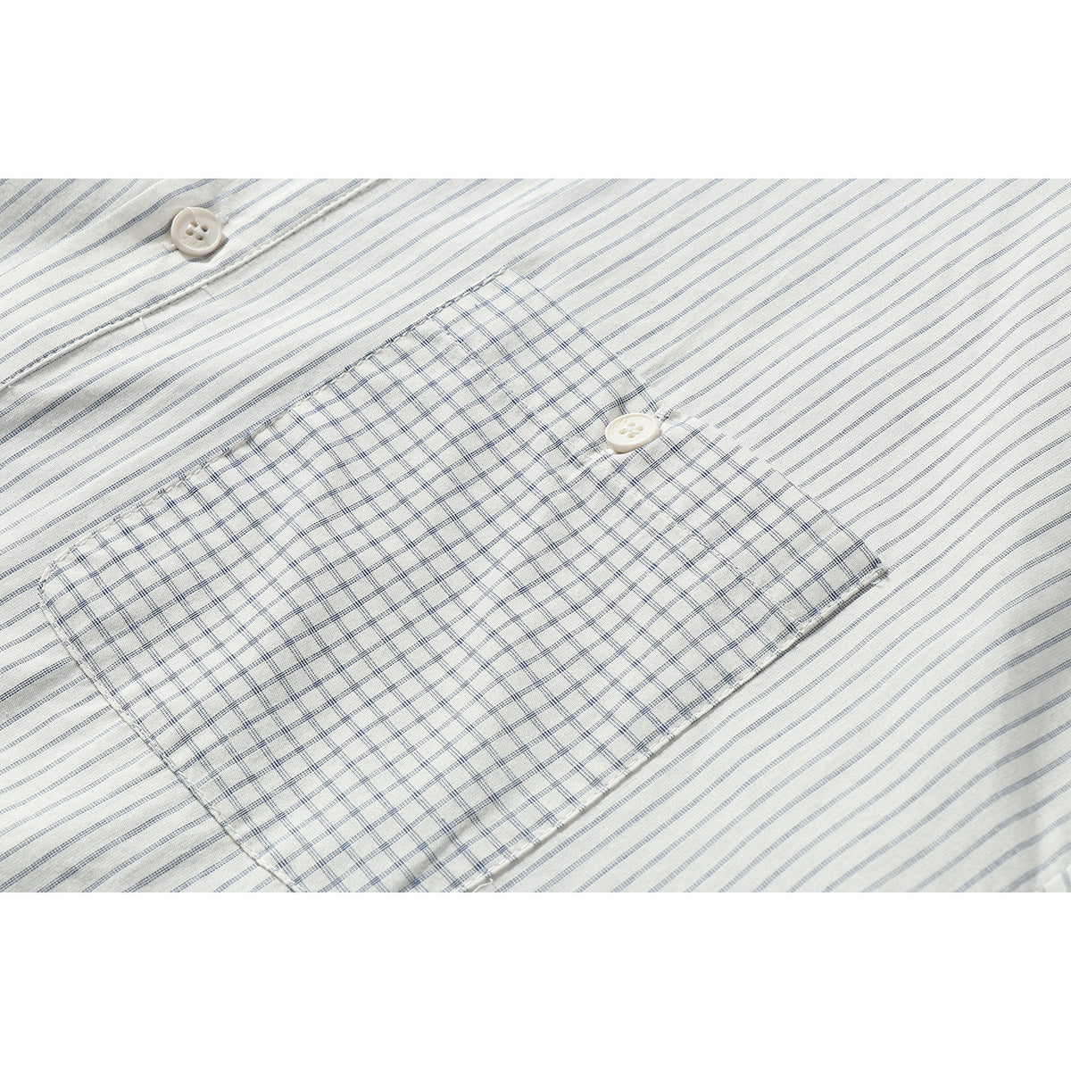 Close-up of a checked chest pocket with a button on an off-white, gray-striped shirt.