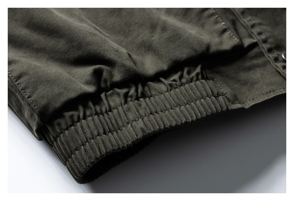 Close-up of a dark olive jacket's gathered elastic hem and textured fabric.