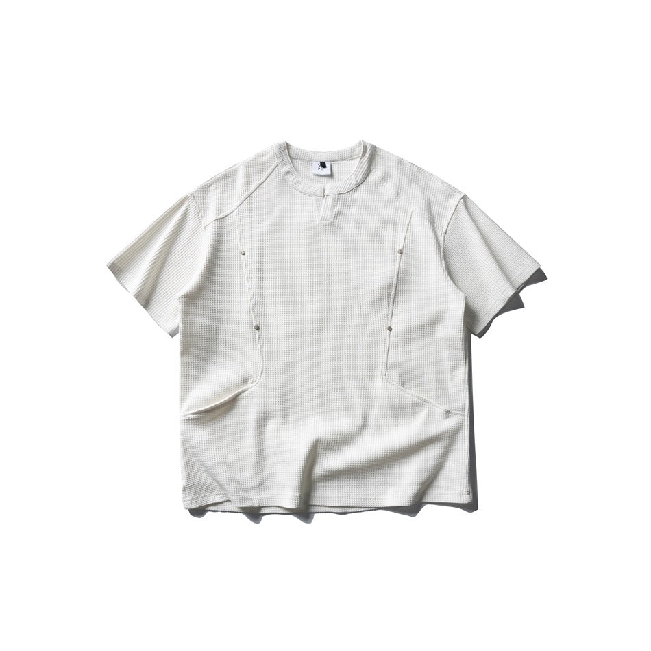 White waffle-textured short-sleeve T-shirt, flat lay, with metal studs, seam details and curved lower front seams
