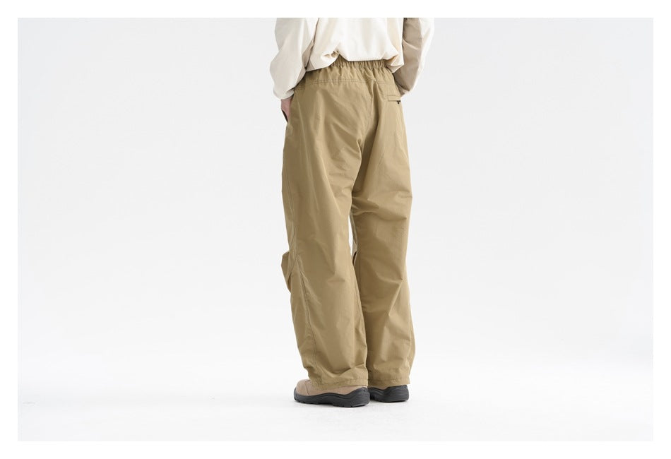 Back view of a model wearing loose khaki pants with an elastic waistband and a small rear pocket.