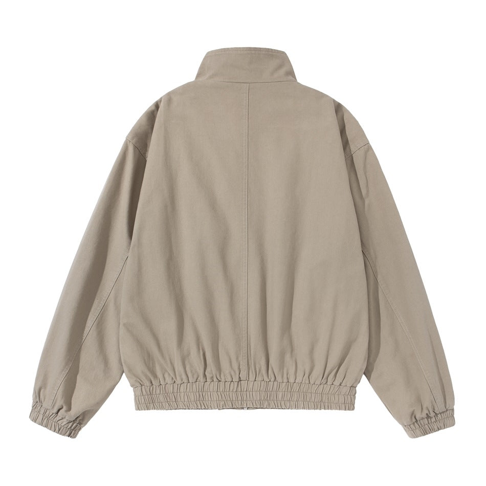 Back view of a beige jacket laid flat, showing a stand collar, center seam, and gathered hem and cuffs.