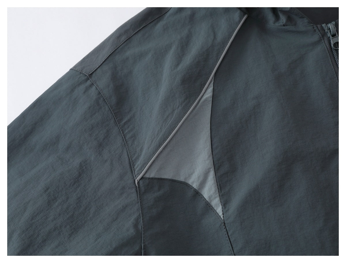 Close-up of a charcoal gray jacket side panel with a light gray triangular inset and piping.