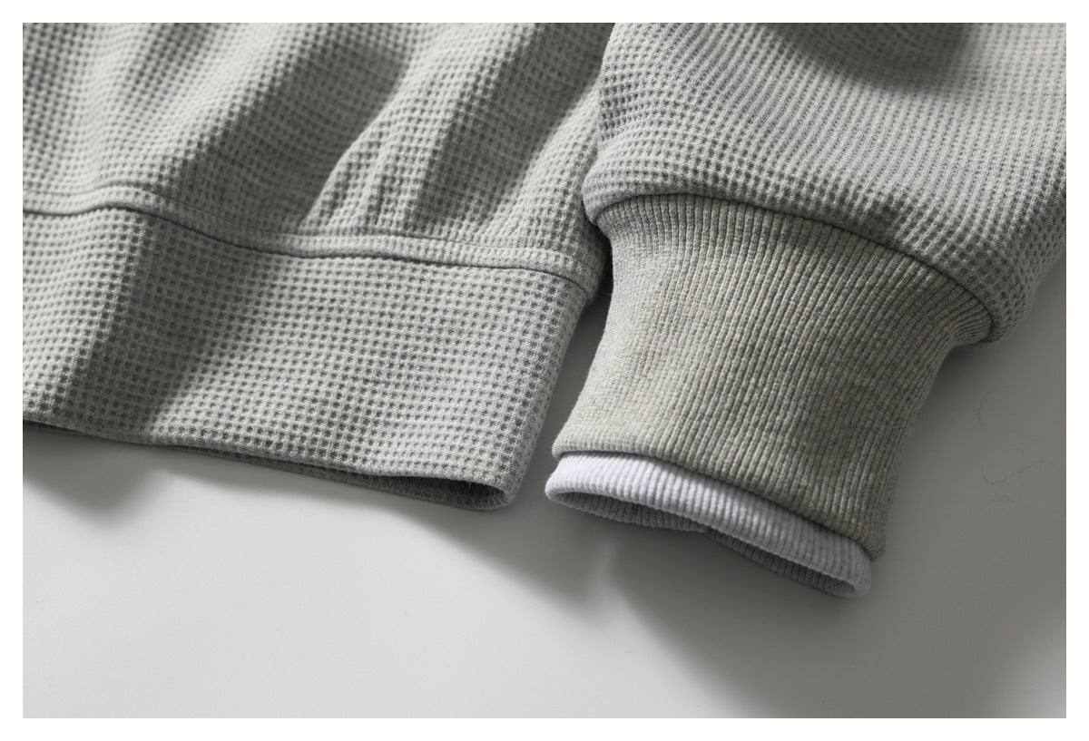 Close-up of the light gray textured top's ribbed cuff and hem.