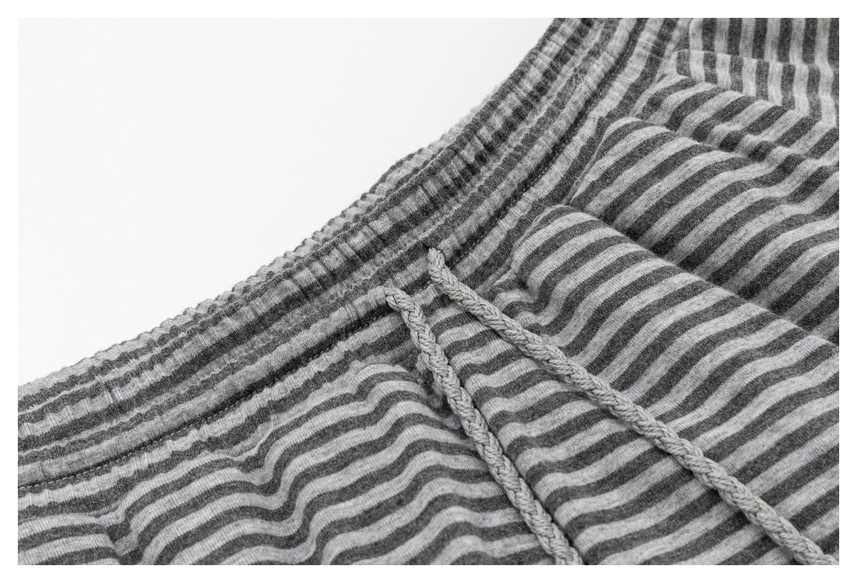 Close-up of a gray-and-charcoal striped garment with an elasticized waistband and braided drawstrings.