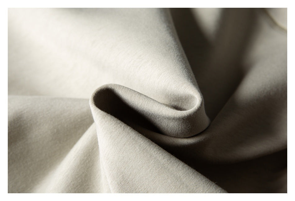 Close-up of light beige fabric folded into a curve, highlighting its fine texture and drape.