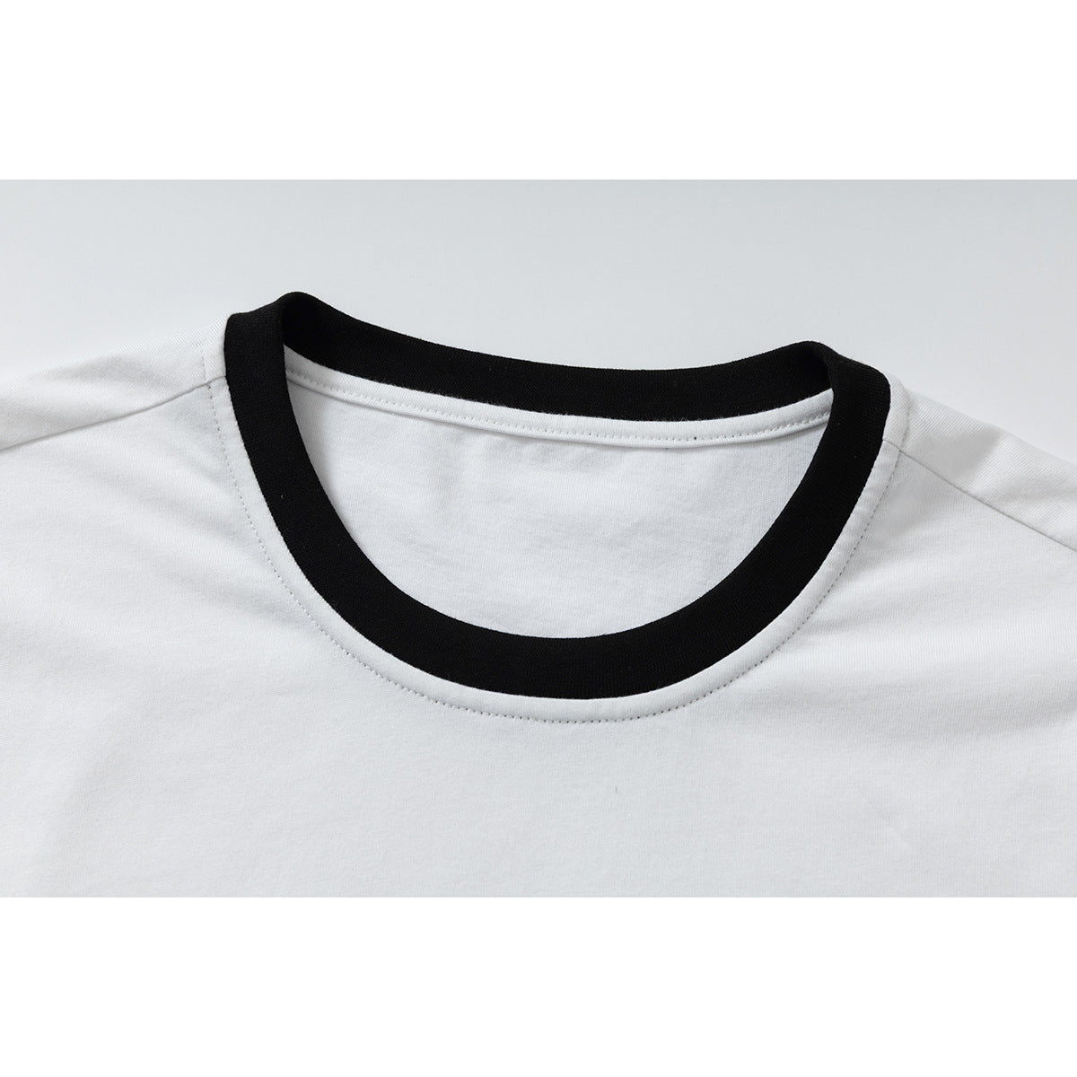Close-up of a white T-shirt’s round neckline with a wide black ribbed trim.