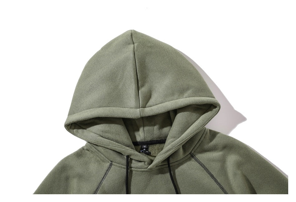 Close-up of an olive green hoodie’s hood, black drawstrings, and raglan shoulder seams.