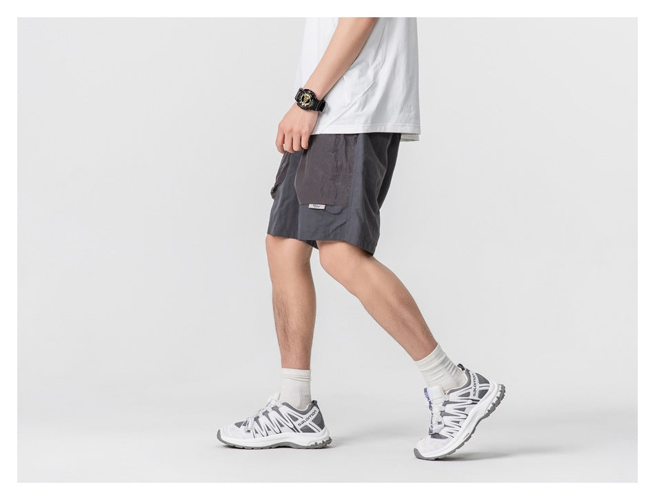 Side view of a person wearing dark gray shorts with a large side cargo pocket.