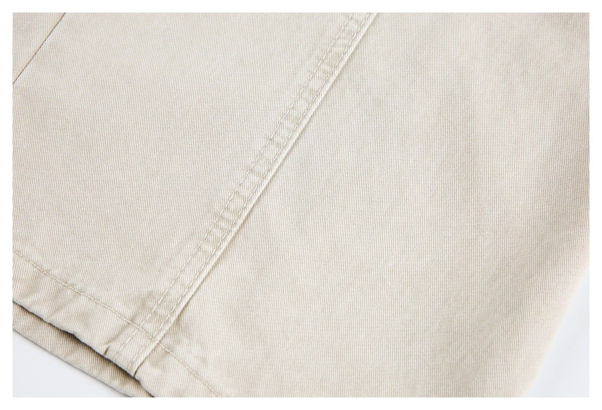 Close-up of stitched seams and a folded edge on light beige pants.