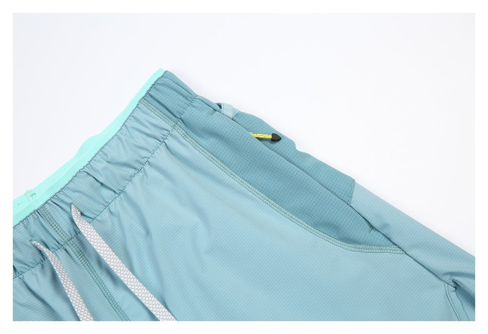 Close-up of aqua shorts showing the elastic waistband, patterned drawcords, and a darker perforated panel.