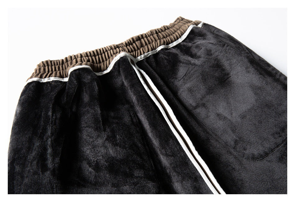Close-up of black trousers with white piping, a patch pocket, and a tan elastic waistband.