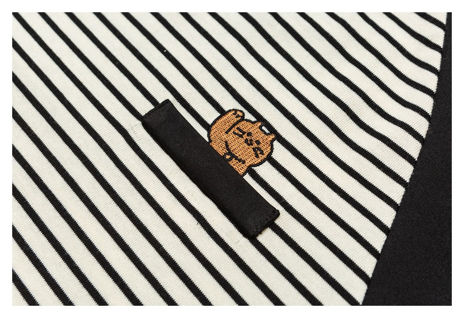 Close-up of an orange embroidered character and black tab on cream-and-black striped fabric.
