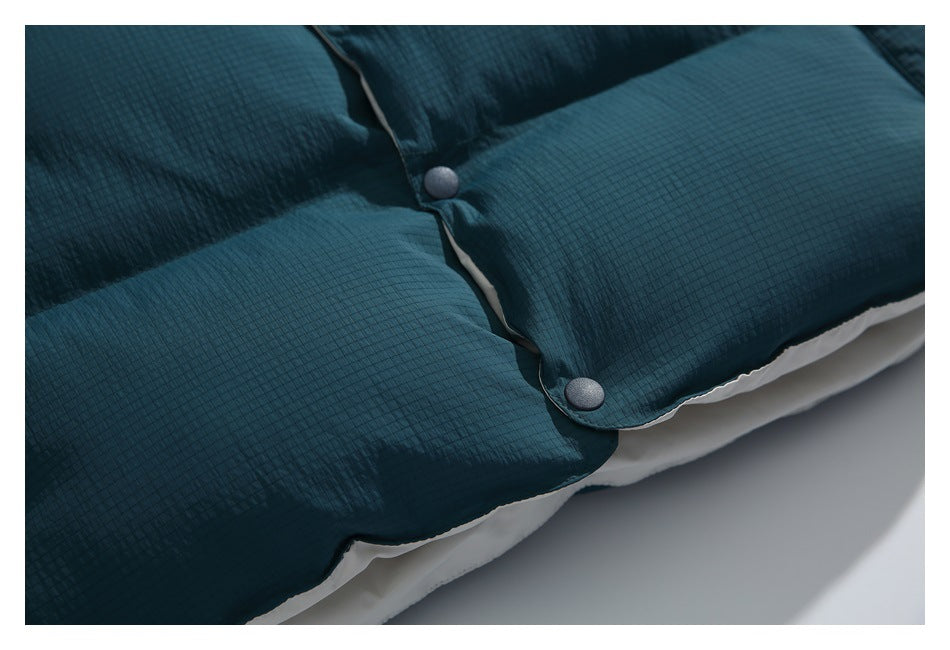 Close-up of a dark teal quilted garment with two dark snap fasteners and white lining visible at the edge.