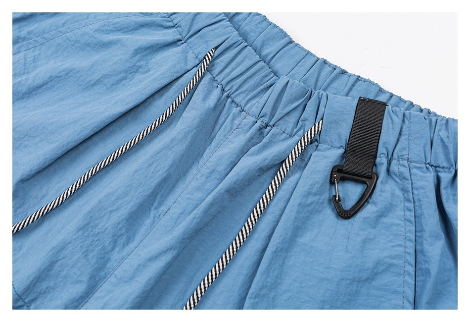 Close-up of blue shorts with an elastic waistband, black-and-white drawstrings, and a black clip attached at the waist.