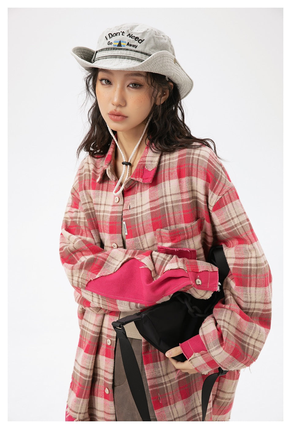 Model wearing a red, beige and brown plaid oversized shirt with bright pink panels and a chest pocket.