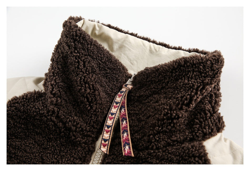 Close-up of a brown fleece jacket's high collar, cream lining, and patterned zipper pull.