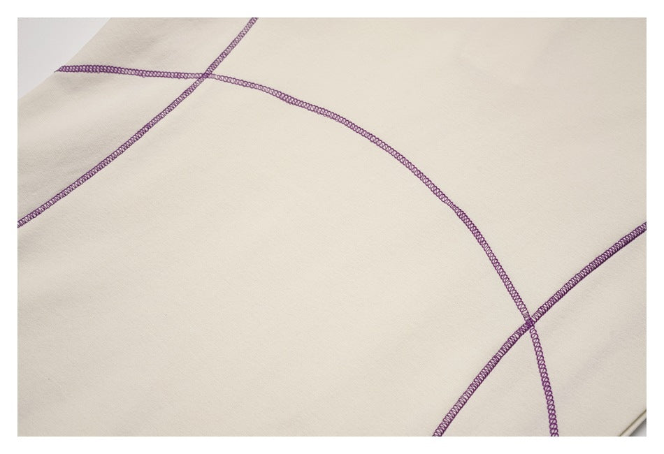 Ivory garment close-up showing curved and intersecting purple overlock seams.