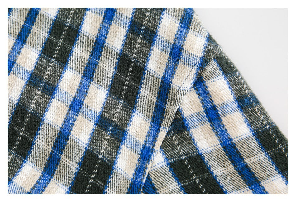 Close-up of blue, cream and dark green plaid fabric and a stitched seam.