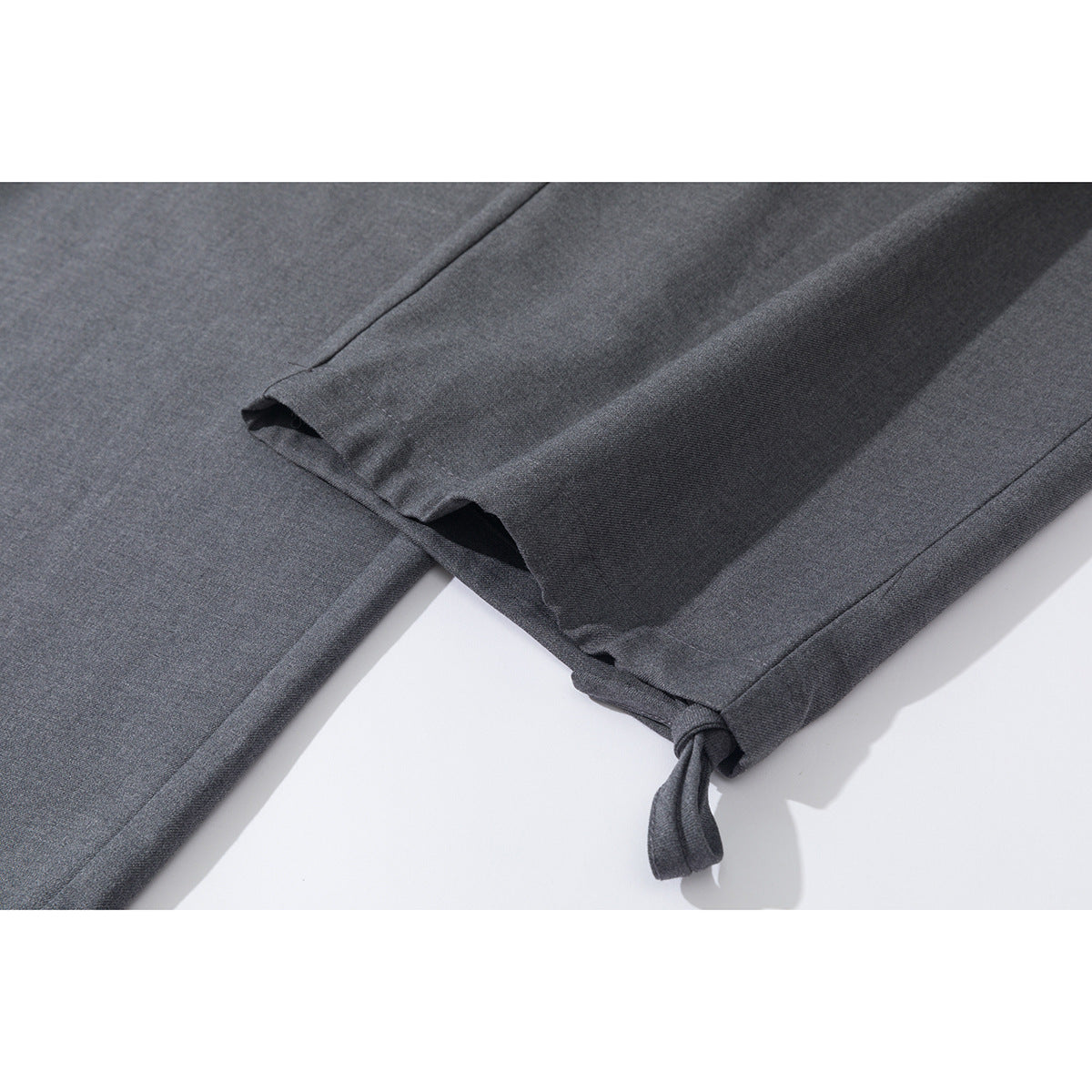 Close-up of a charcoal gray trouser leg hem with an adjustable fabric tie.